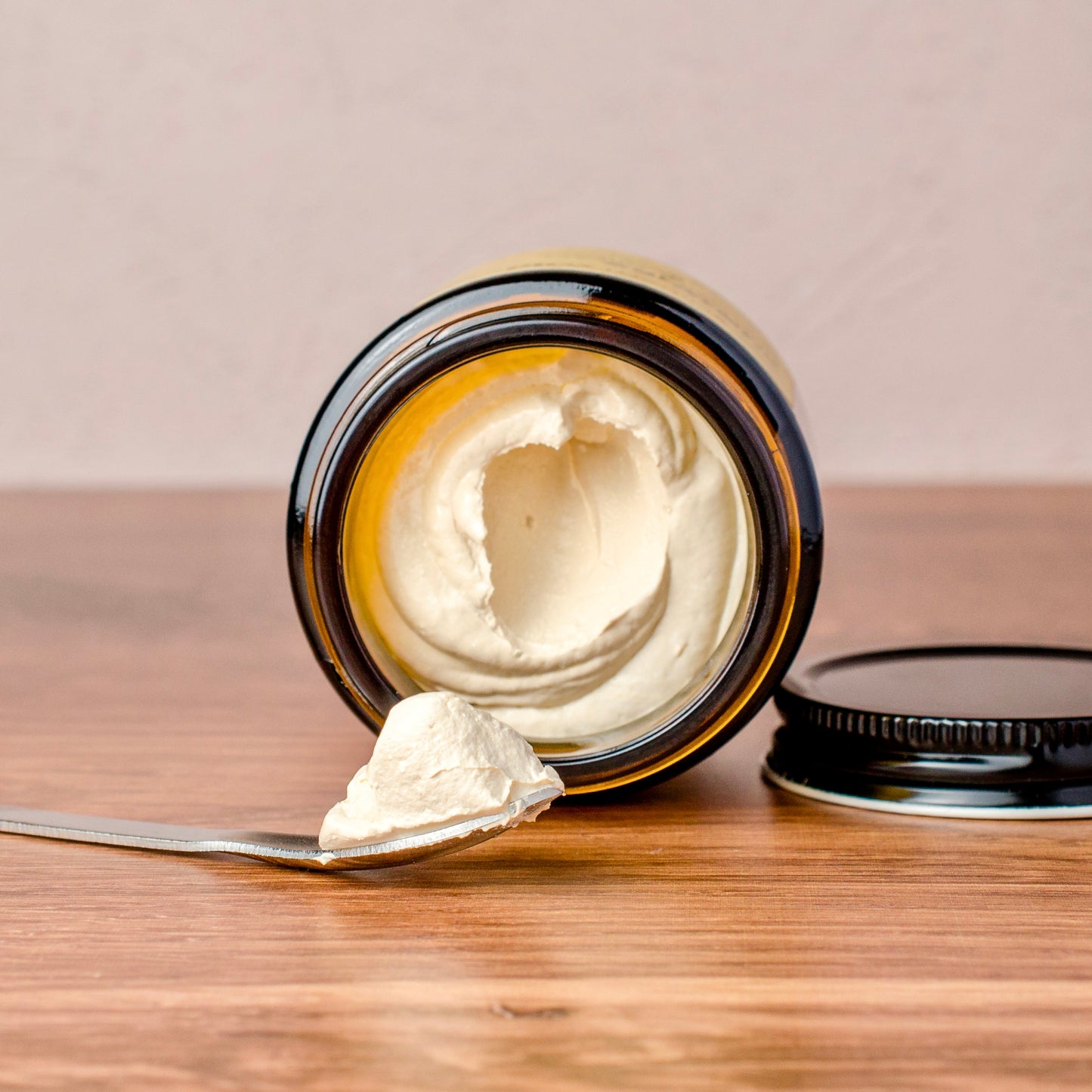 Jar of zinc oxide cream with a spoonful on a wooden surface