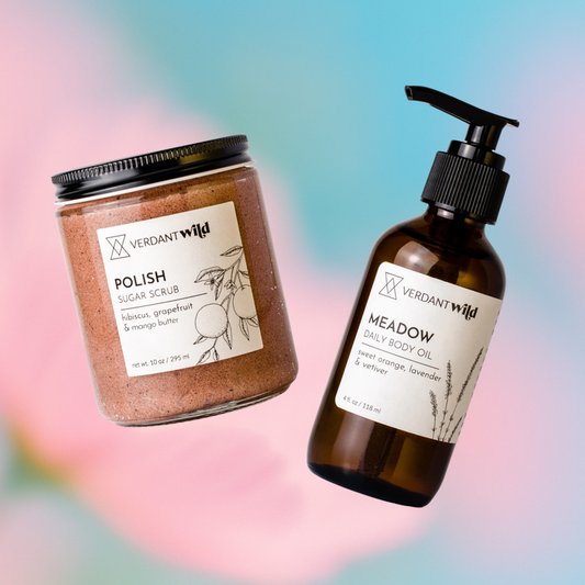 Verdant Wild sugar scrub jar and body oil bottle on a colorful gradient background