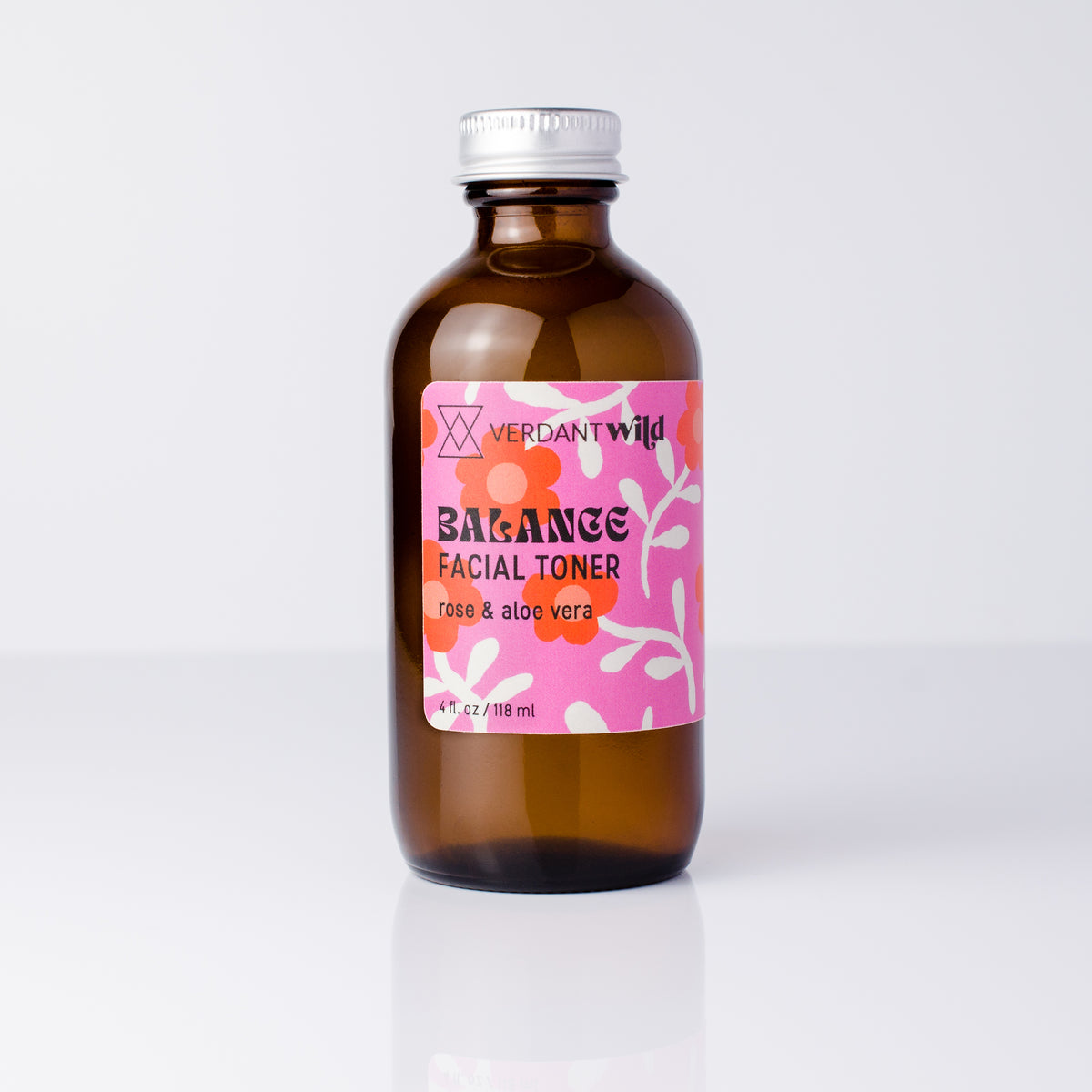 A 4 oz amber glass bottle of Verdant Wild Balance Facial Toner with a pink floral label and silver cap, set against a clean white background.