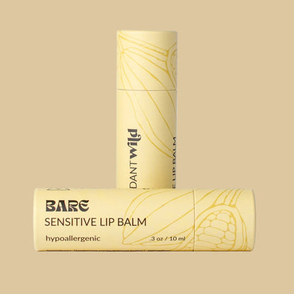 Bare Sensitive Lip Balm in a pale yellow tube with gold leaf line art and black text, shown both upright and horizontal on a solid beige background.