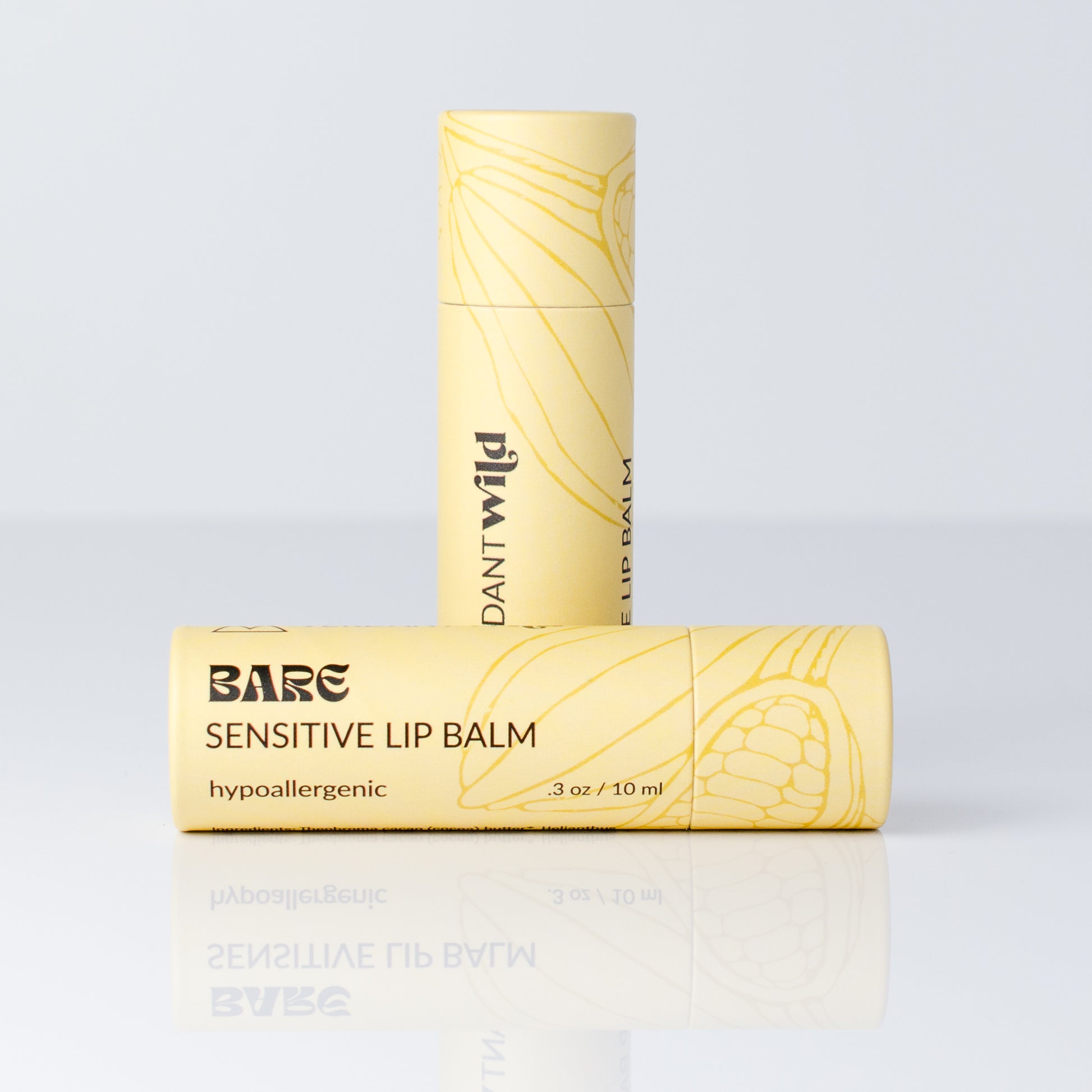 Two tubes of Bare Lip Balm in a pale yellow color with black text and a yellow botanical line drawing, displayed on a reflective white surface against a light gray background.