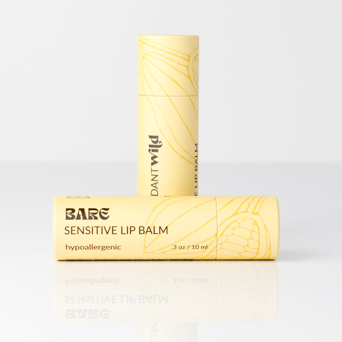 Two pale yellow lip balm tubes on a clean white studio background. One tube stands upright behind the other, which is lying horizontally.
