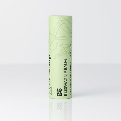 A single tube of Beeswax Lip Balm in a pale mint green color, standing upright on a reflective white surface against a light gray background.