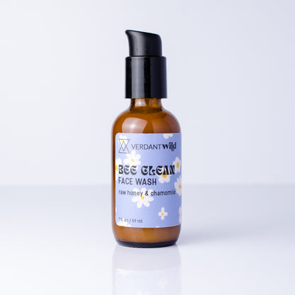 A 2 fl oz amber glass bottle of Verdant Wild Bee Clean Face Wash with a black pump dispenser and a light purple label, set against a clean white background with a soft reflection.