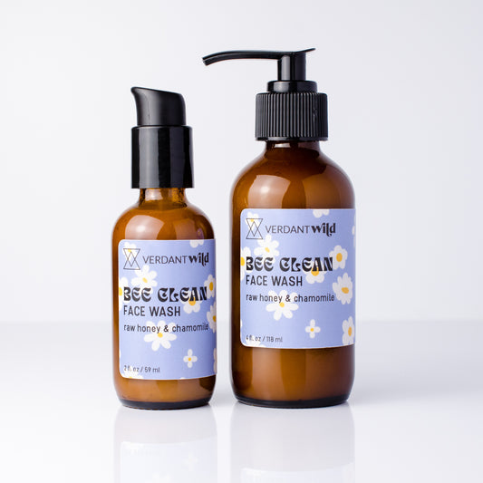 Two amber glass face wash bottles with black pumps on a white background. The smaller bottle has a black treatment pump, and the larger bottle has a bigger black pump.