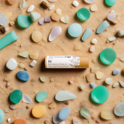 mint clary sage beeswax lip balm on beach with micro plastics