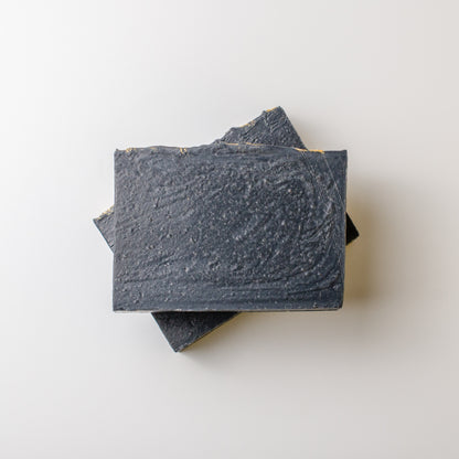Three bars of dark soap stacked on a light gray background