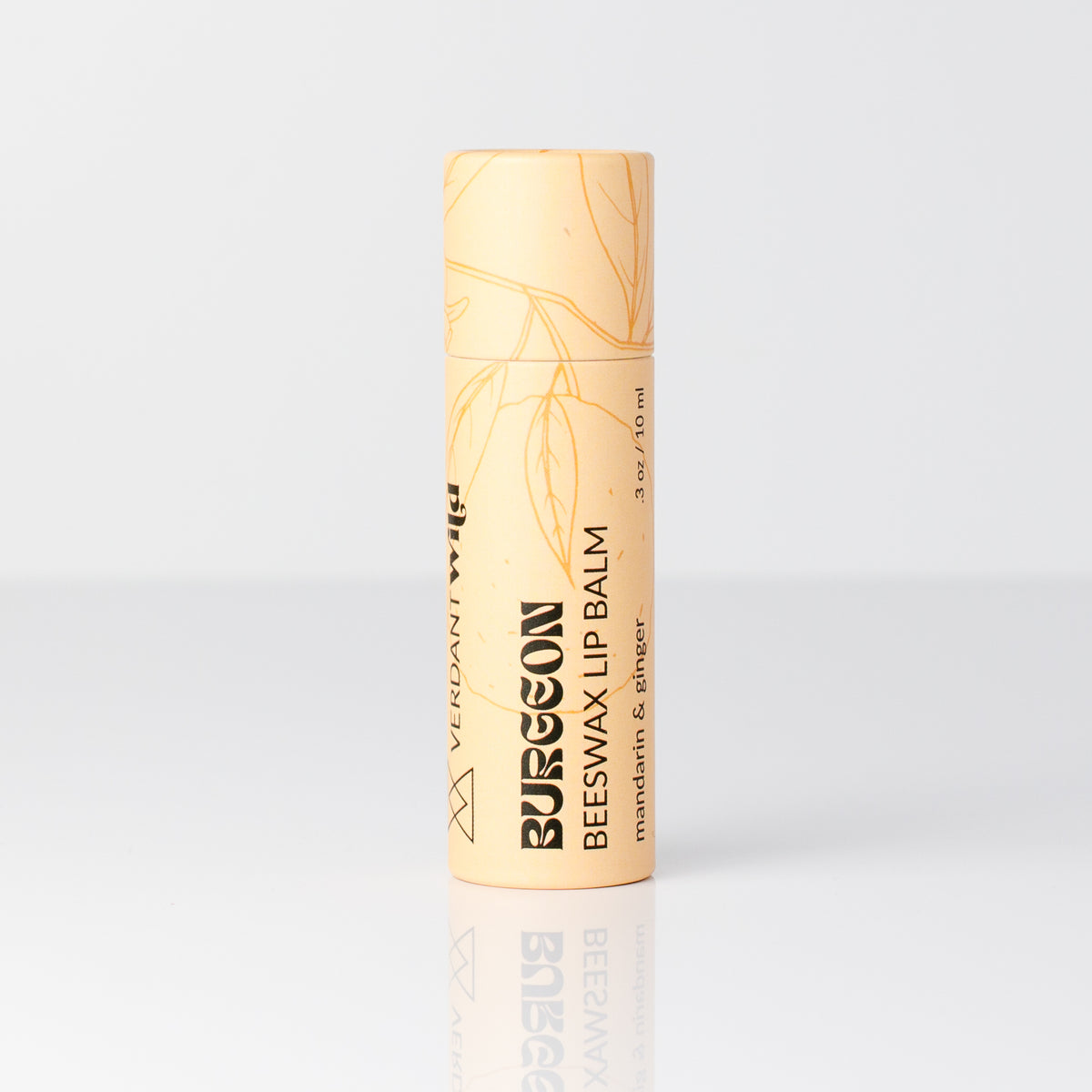 A single tube of Burgeon Beeswax Lip Balm with a pale peach-beige cap and body, featuring gold botanical line art and black text, set against a clean white background with a soft reflection below.