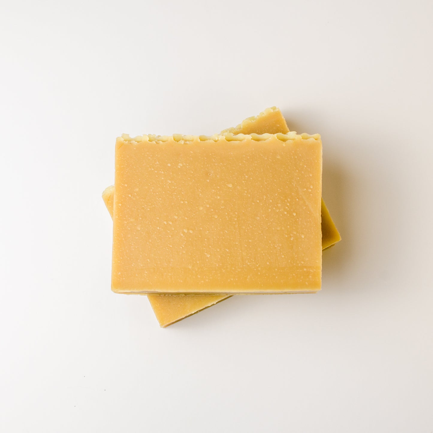 Two yellow soap bars stacked on a white background