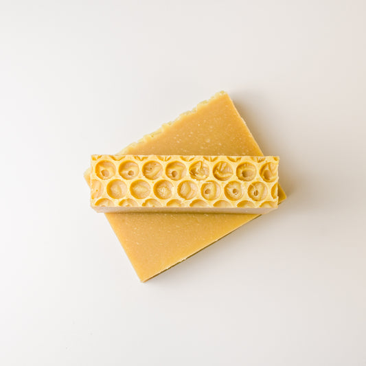 Two bars of yellow soap with a honeycomb pattern on a white background