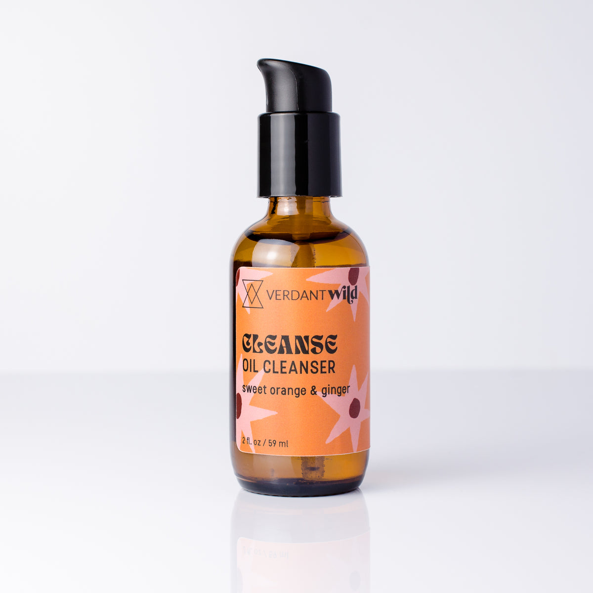 A bottle of Verdant Wild Cleanse Oil Cleanser with a black pump and amber glass bottle, featuring a peach and orange label with graphics, set against a clean white background.