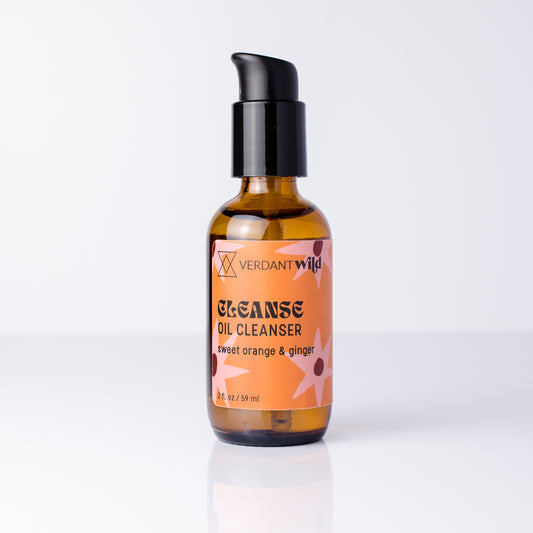 A bottle of Verdant Wild Cleanse Oil Cleanser with a black pump and amber glass bottle, featuring a peach and orange label with graphics, set against a clean white background.