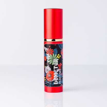 A perfume bottle with a metallic red cap and base, featuring a black label decorated with colorful floral illustrations.