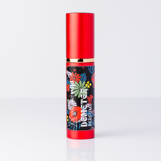 A perfume bottle with a metallic red cap and base, featuring a black label decorated with colorful floral illustrations.