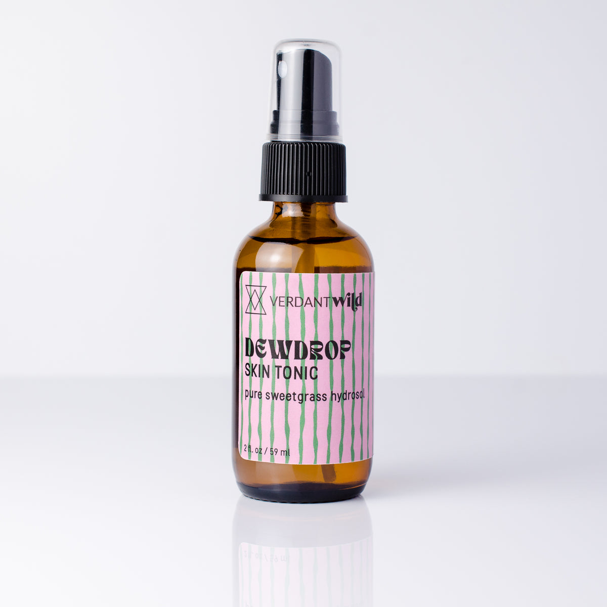 A 2 fl oz amber glass spray bottle of Verdant Dewdrop Skin Tonic with a black spray cap and a pink and white striped label, set against a clean white background with a soft reflection.