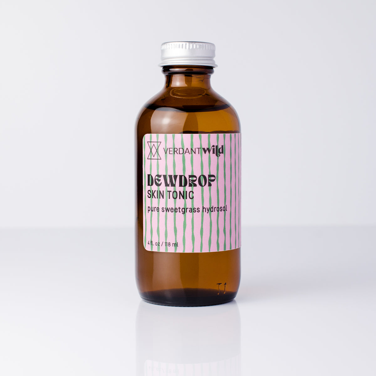 A 4 fl oz amber glass bottle of Verdant Wild Dewdrop Skin Tonic with a silver cap and a pink and green striped label, set against a clean white background.