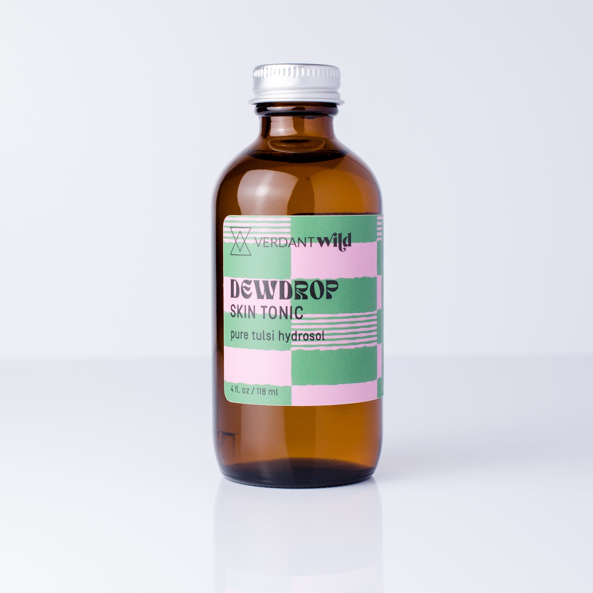 A 4 fl oz amber glass bottle of Verdant Wild Tulsi Skin Tonic with a silver cap and a pink, green, and white checkered label, set against a clean white background.