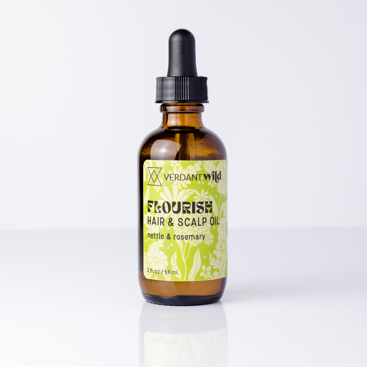 A 2 oz amber glass dropper bottle of Verdant Wild Flourish Hair & Scalp Oil, featuring a black dropper cap and a light green and white floral label, set against a clean white background with a soft reflection.