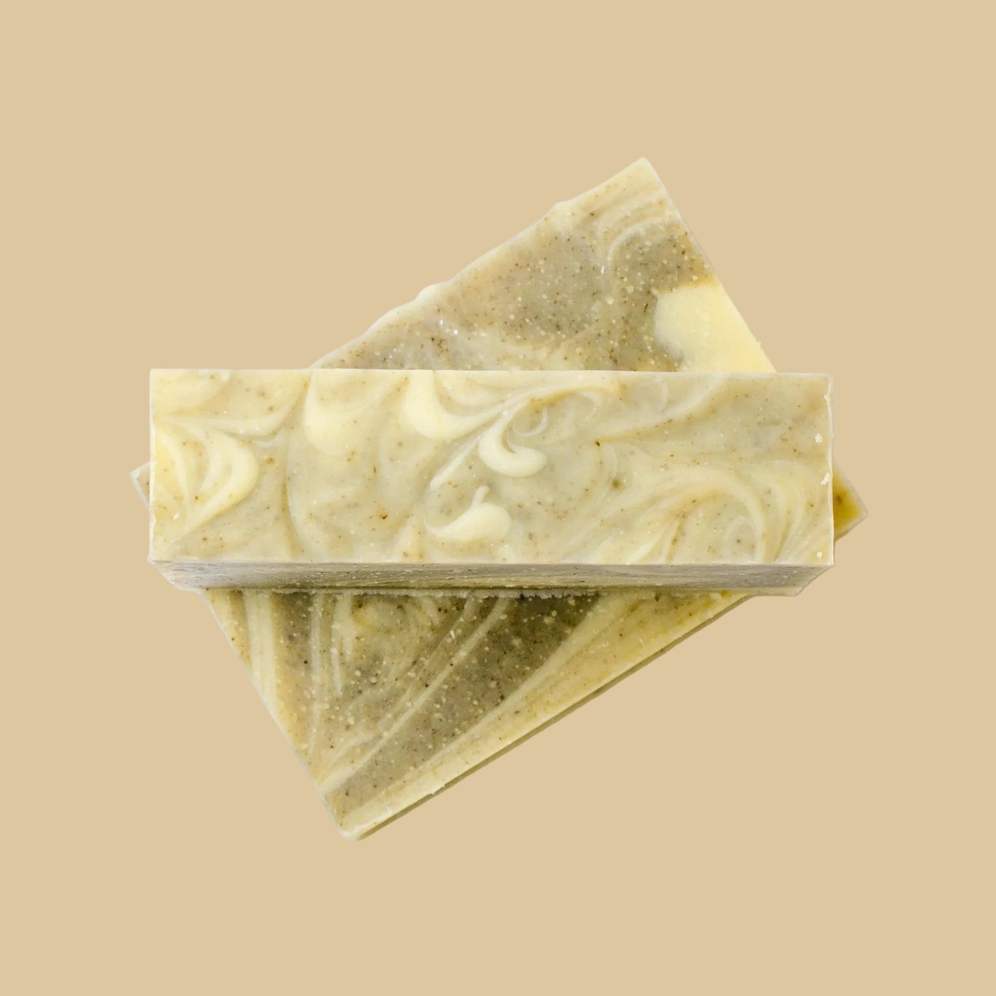 Two stacked rectangular bars of handmade soap with a marbled swirl pattern of cream, olive green, and yellow, set against a plain background.