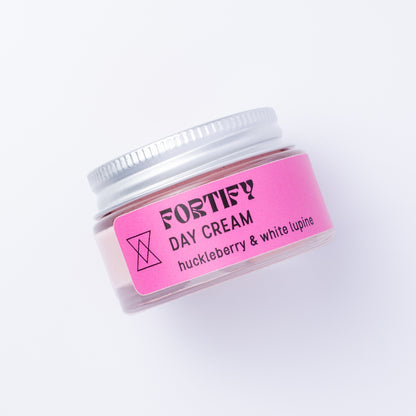 A small clear jar of Fortify Day Cream with a silver lid and a bright pink label, photographed on a clean white background.