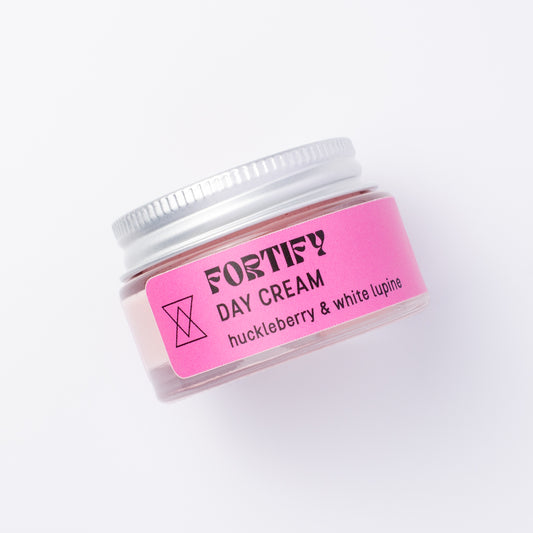 A small clear jar of Fortify Day Cream with a silver lid and a bright pink label, photographed on a clean white background.