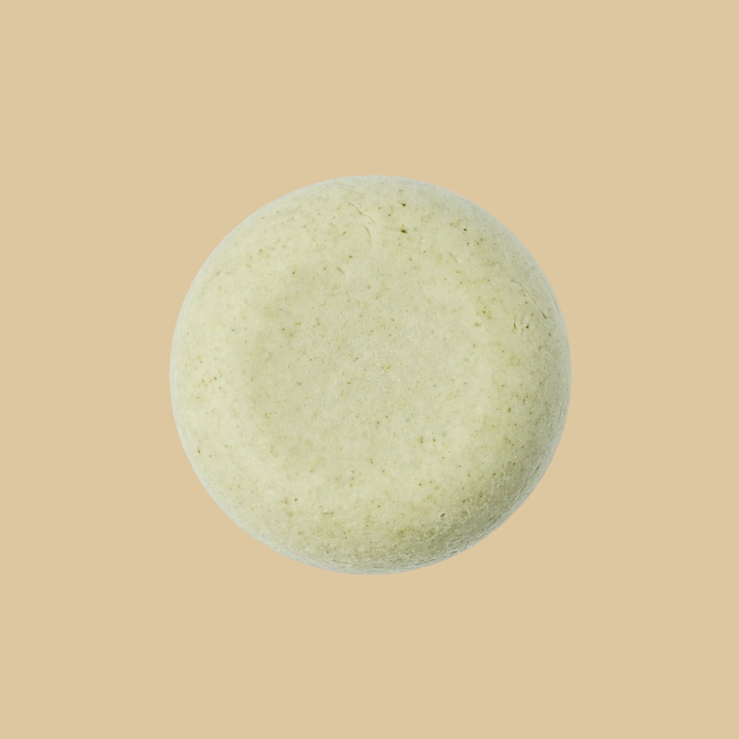 A single round, pale sage green shampoo bar with a textured, matte surface, photographed from directly above on a plain background.