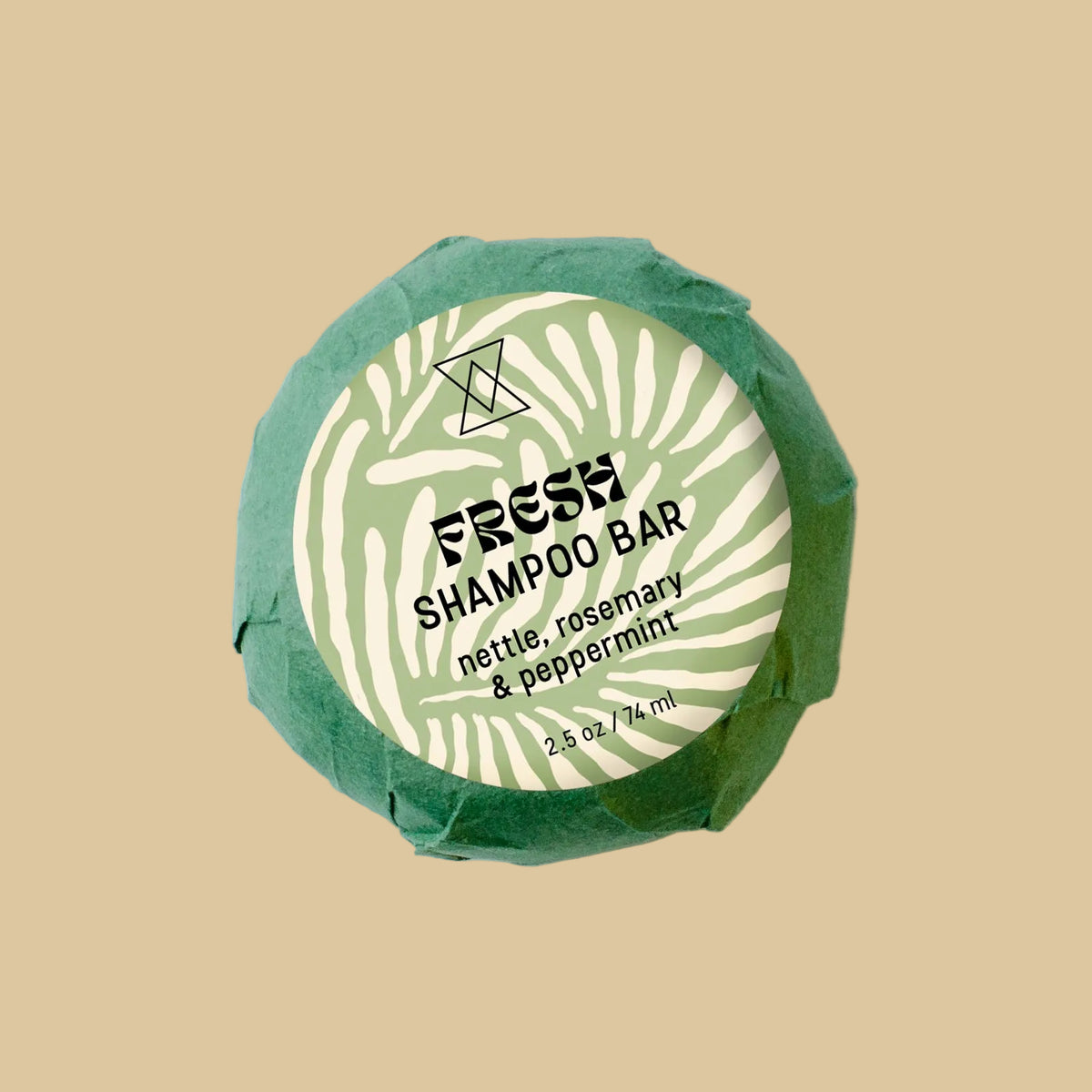 A round wrapped shampoo bar on a clean background. The product is wrapped in textured green paper with a white circular label reading 'FRESH SHAMPOO' and 'nettle, rosemary & peppermint'.