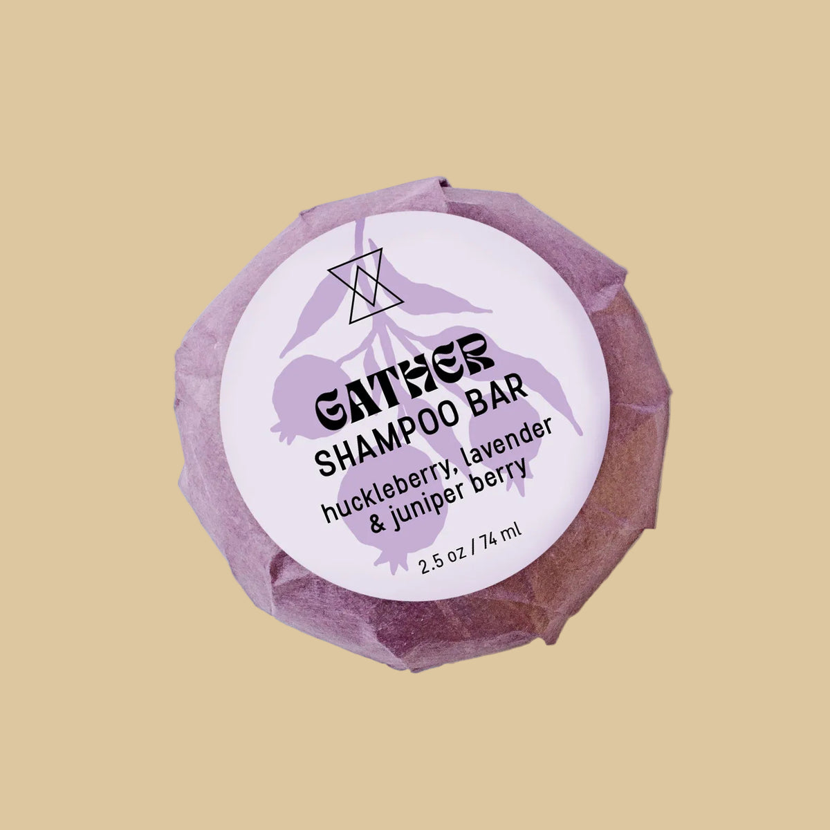 A single wrapped bar of shampoo on a clean background. The product is wrapped in a textured, faceted dusty purple paper wrapper with a white circular label reading 'GATHER SHAMPOO' and 'huckleberry, lavender & juniper berry'.