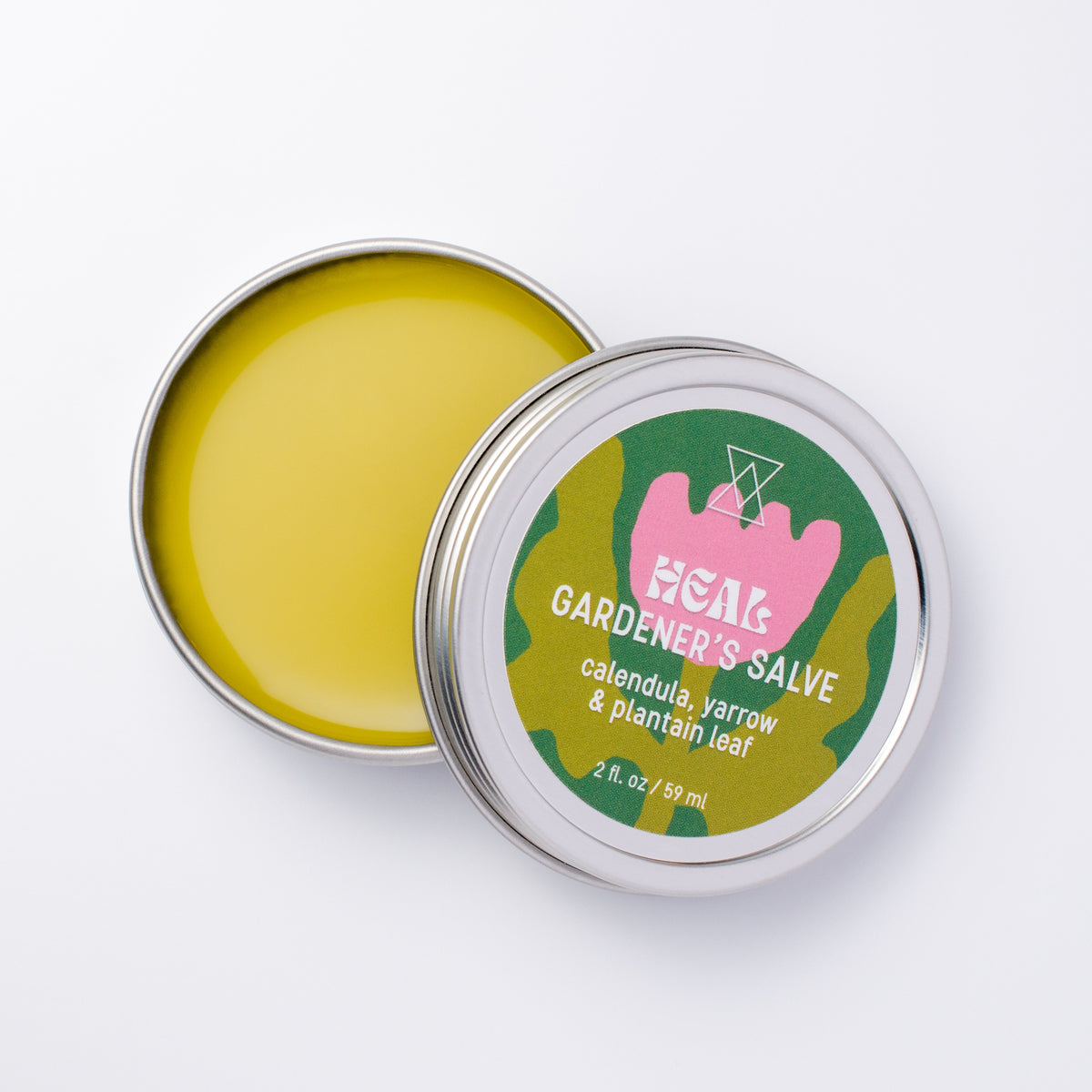 An open round metal tin of GARDENER'S SALVE showing the yellow-green balm inside, with the lid displaying a colorful label on a clean white background.