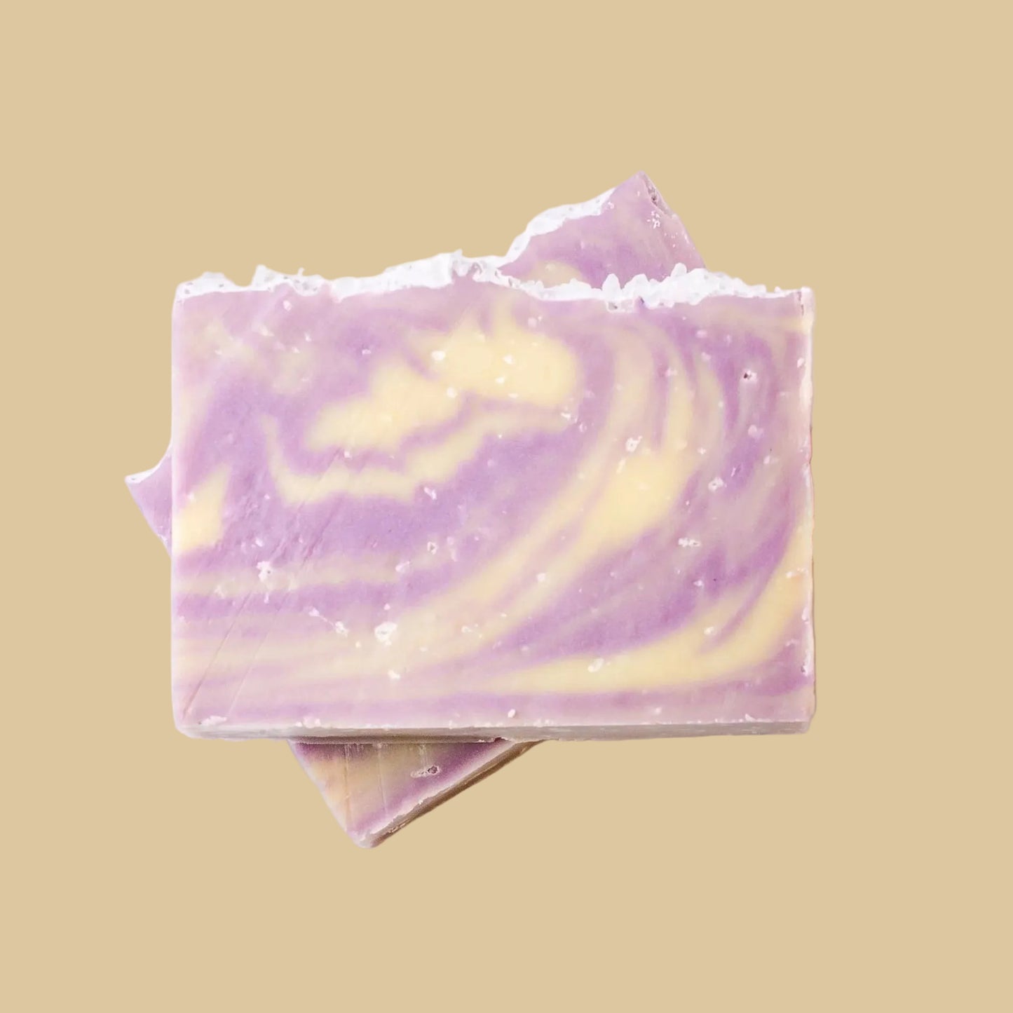 A stack of handmade soap bars with a marbled swirl pattern of lavender purple and pale yellow, set against a plain background.