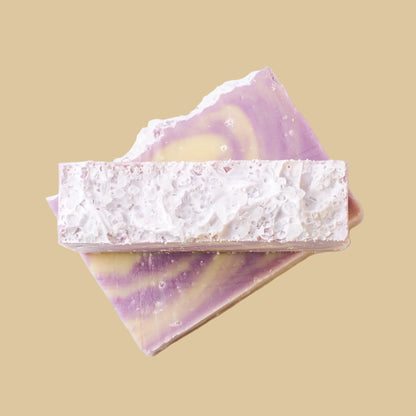 Two rectangular bars of soap stacked on a plain white background. The top bar is textured with a sea salt top, while the bottom bar shows a marbled swirl pattern of lavender purple and pale yellow.