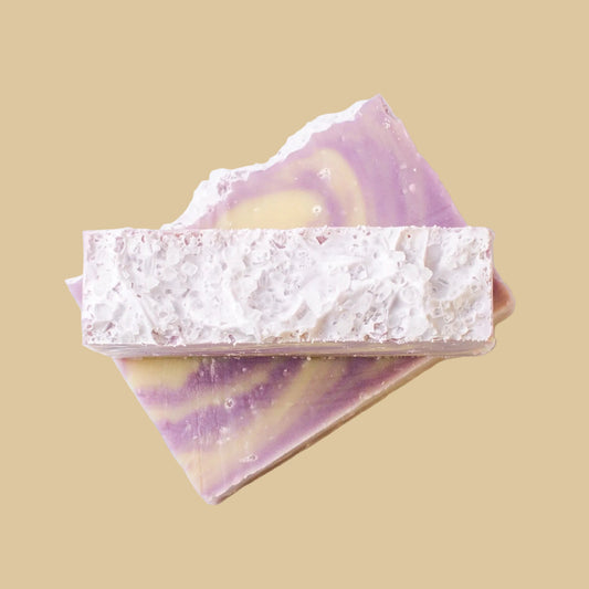 Two rectangular bars of soap stacked on a plain white background. The top bar is textured with a sea salt top, while the bottom bar shows a marbled swirl pattern of lavender purple and pale yellow.