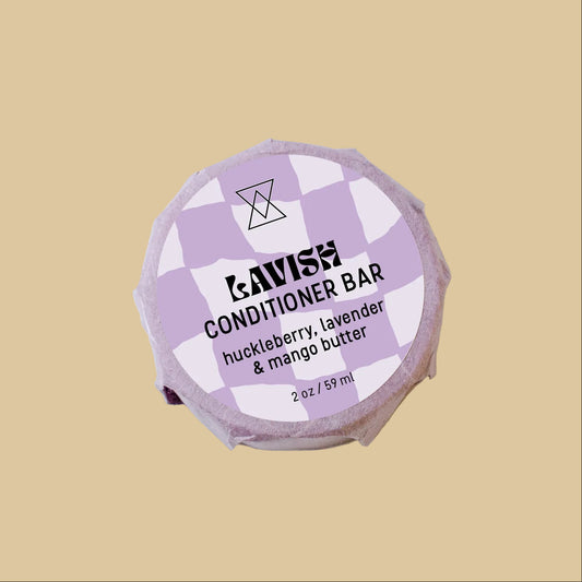 A lavender and white checkered Conditioner Bar wrapped in paper, labeled 'huckleberry, lavender & mango butter' on a clean background.