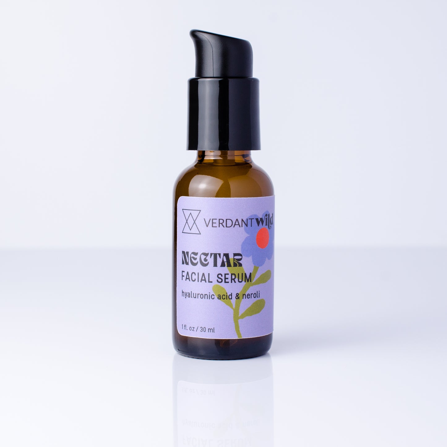 A small amber glass bottle of Verdant Wild Nectar Facial Serum with a black pump dispenser, set against a clean white background with a soft reflection.