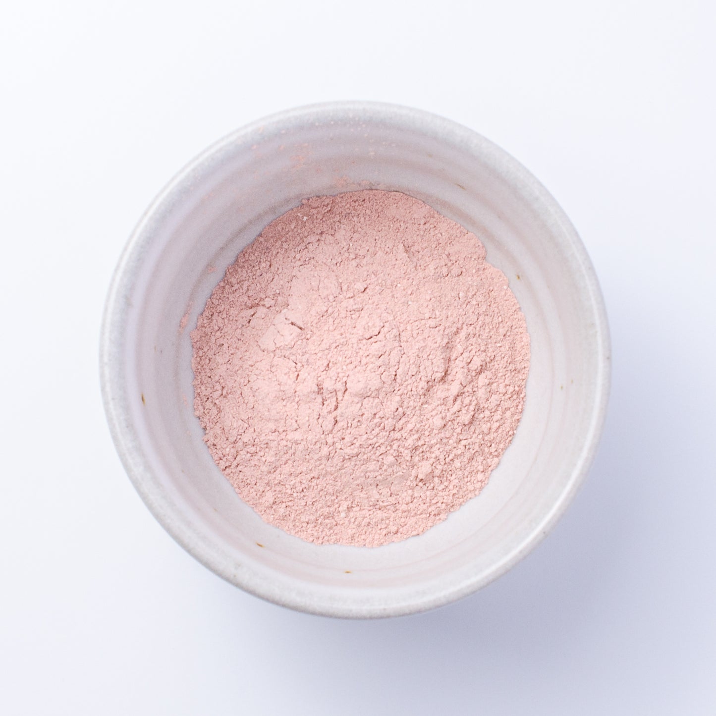 Top down view of Nourish Facial Grains in rose petal and hibiscus powder for scrub or mask.