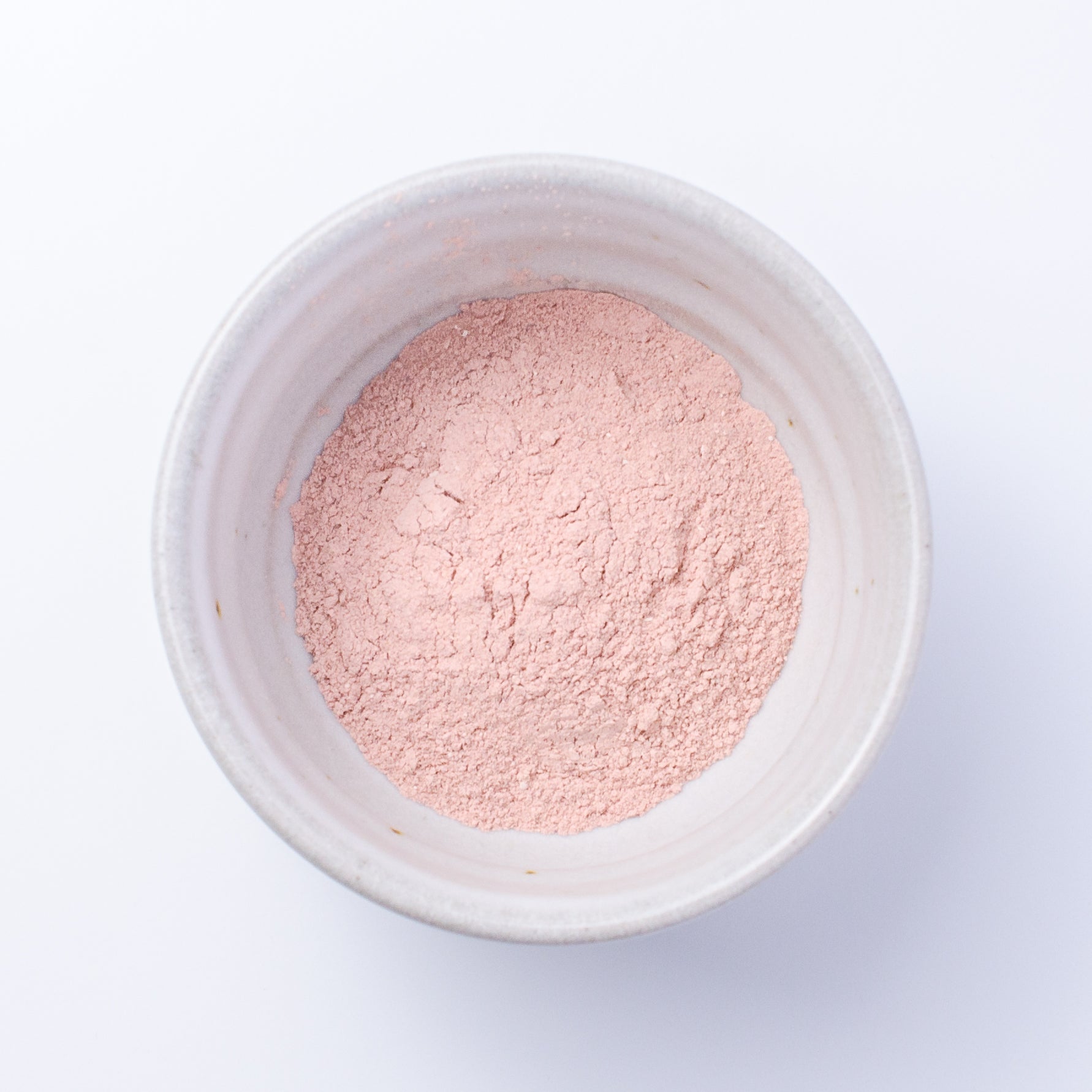 Top down view of Nourish Facial Grains in rose petal and hibiscus powder for scrub or mask.