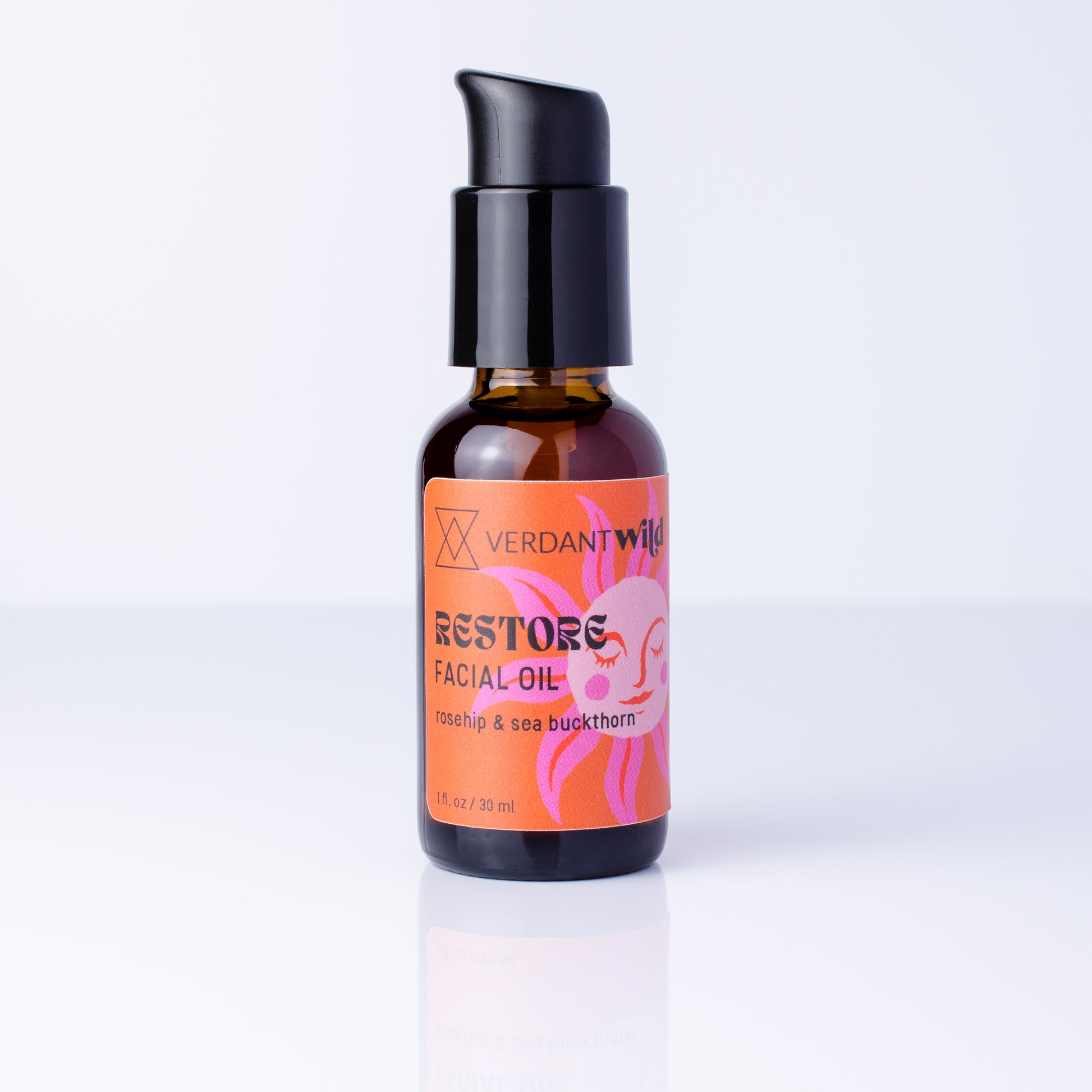 A small amber glass bottle of Verdant Wild Restore Facial Oil with a black pump dispenser and a bright orange label, set against a clean white background.