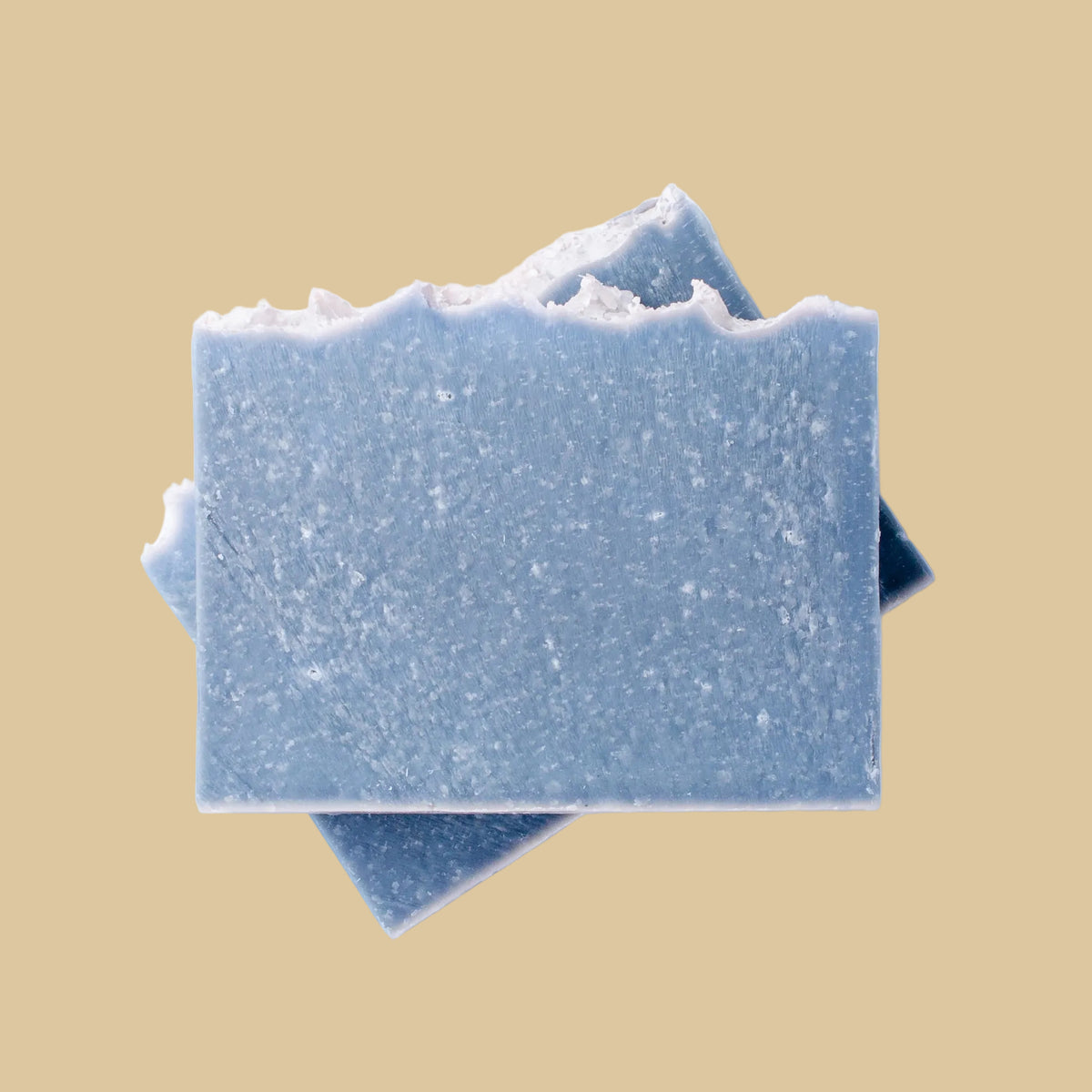 Two rectangular blue soap bars stacked diagonally, with wave pattern and sea salt on top.