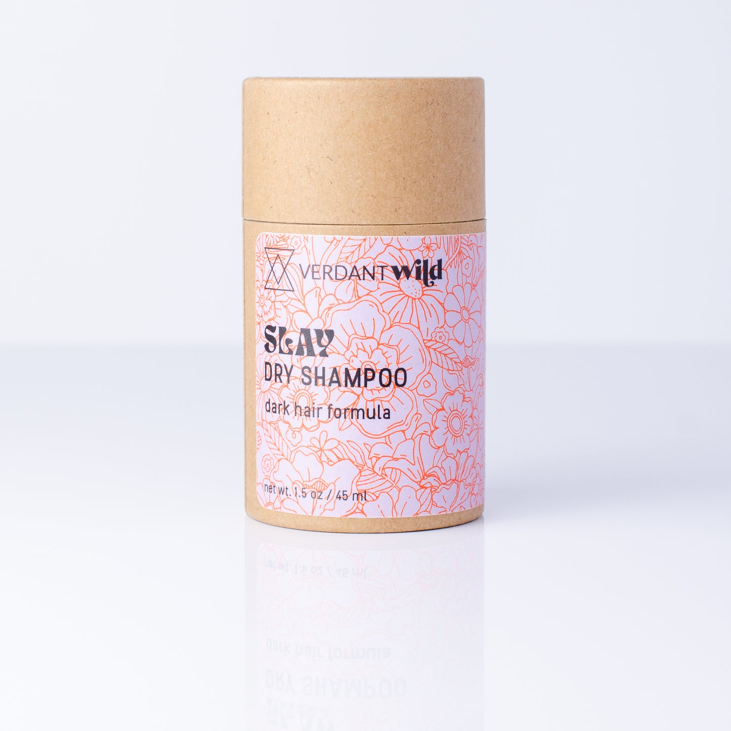 A cylindrical cardboard container of Verdant Wild Slay Dry Shampoo, featuring a kraft brown top and bottom with a pink and red floral patterned label, set against a clean white background with a soft reflection.