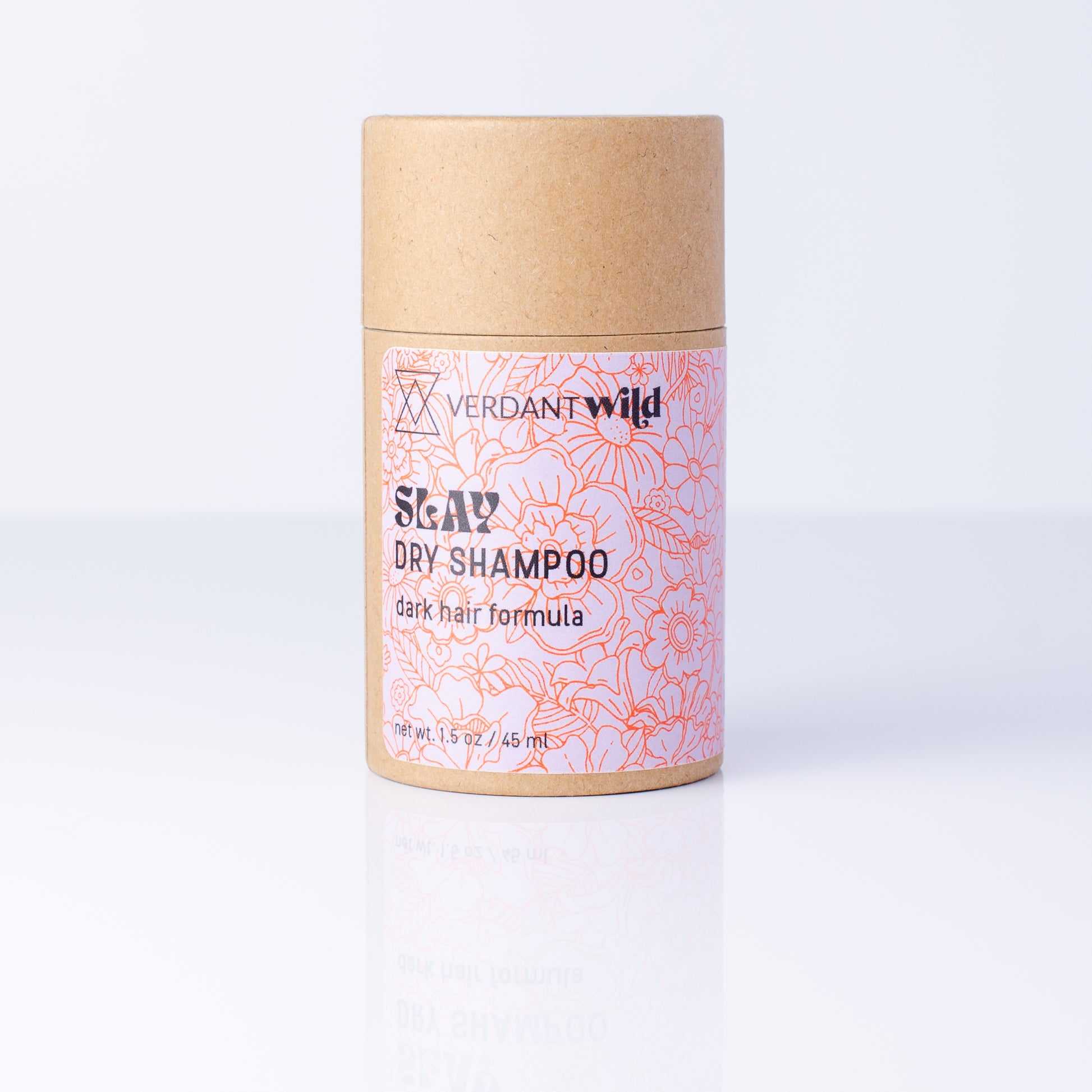 A cylindrical cardboard container of Verdant Wild Slay Dry Shampoo, featuring a kraft brown top and bottom with a pink and red floral patterned label, set against a clean white background with a soft reflection.