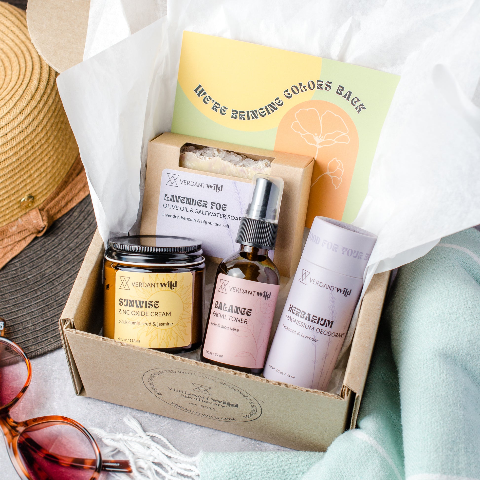 Gift set with skincare products and a hat on a white surface