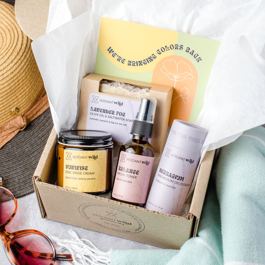 Gift set with skincare products and a hat on a white surface