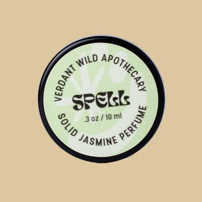A round black-lidded jar of Verdant Wild Apothecary Spell Solid Jasmine Perfume, featuring a pale green label with black text.