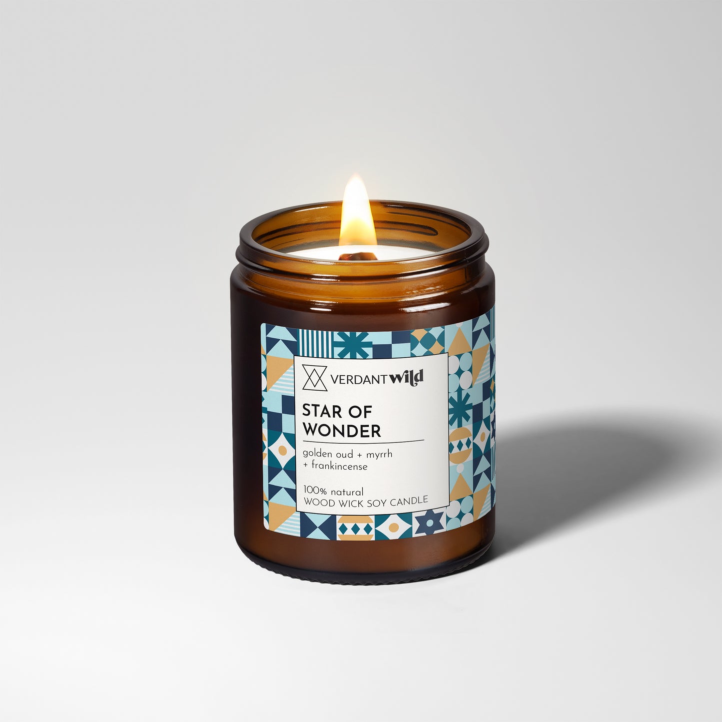 Candle in an amber jar with a decorative label on a light gray background