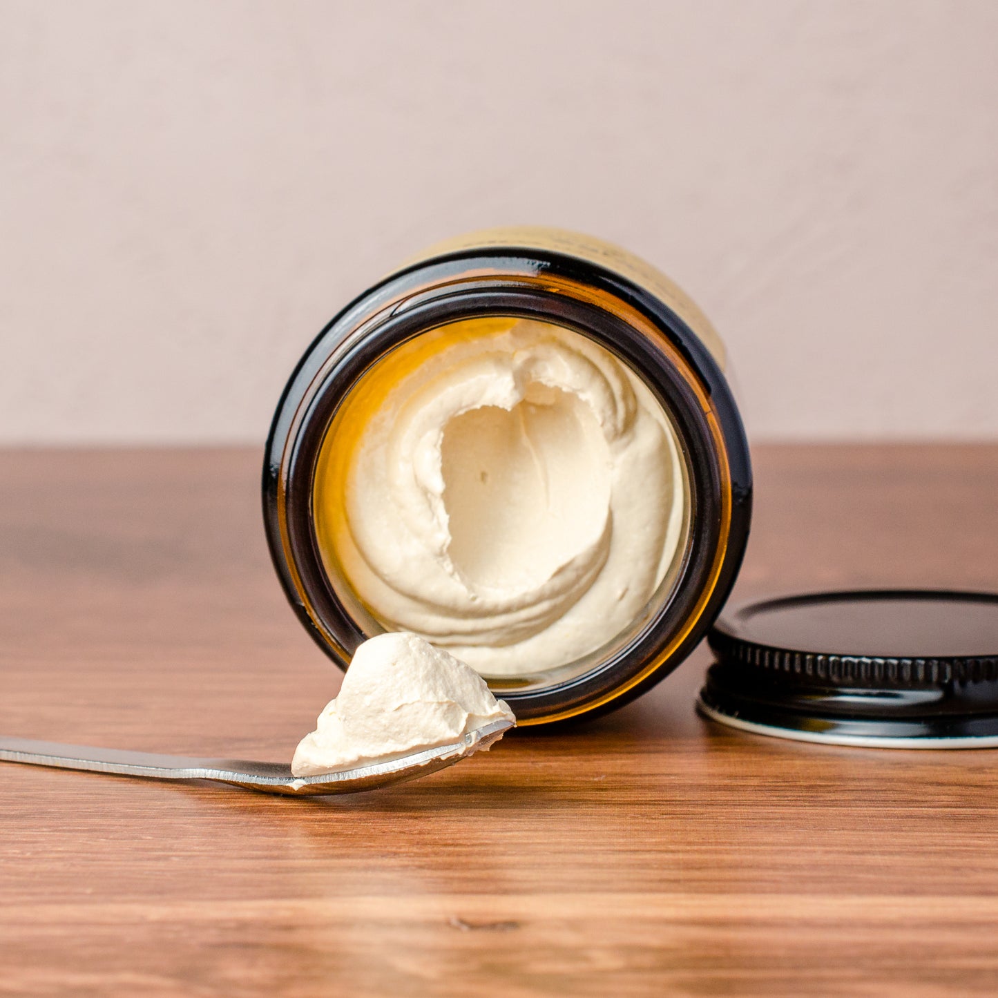Jar of zinc oxide sun cream with a spoonful on a wooden surface