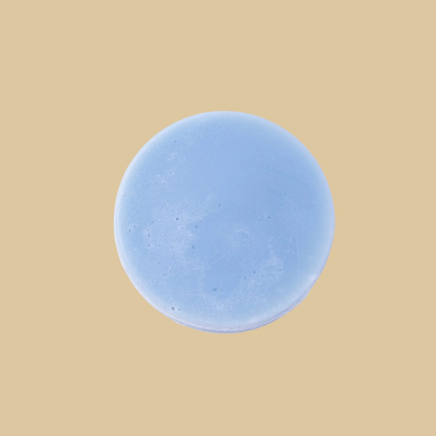 A round, light blue conditioner bar, photographed from directly above on a clean background.