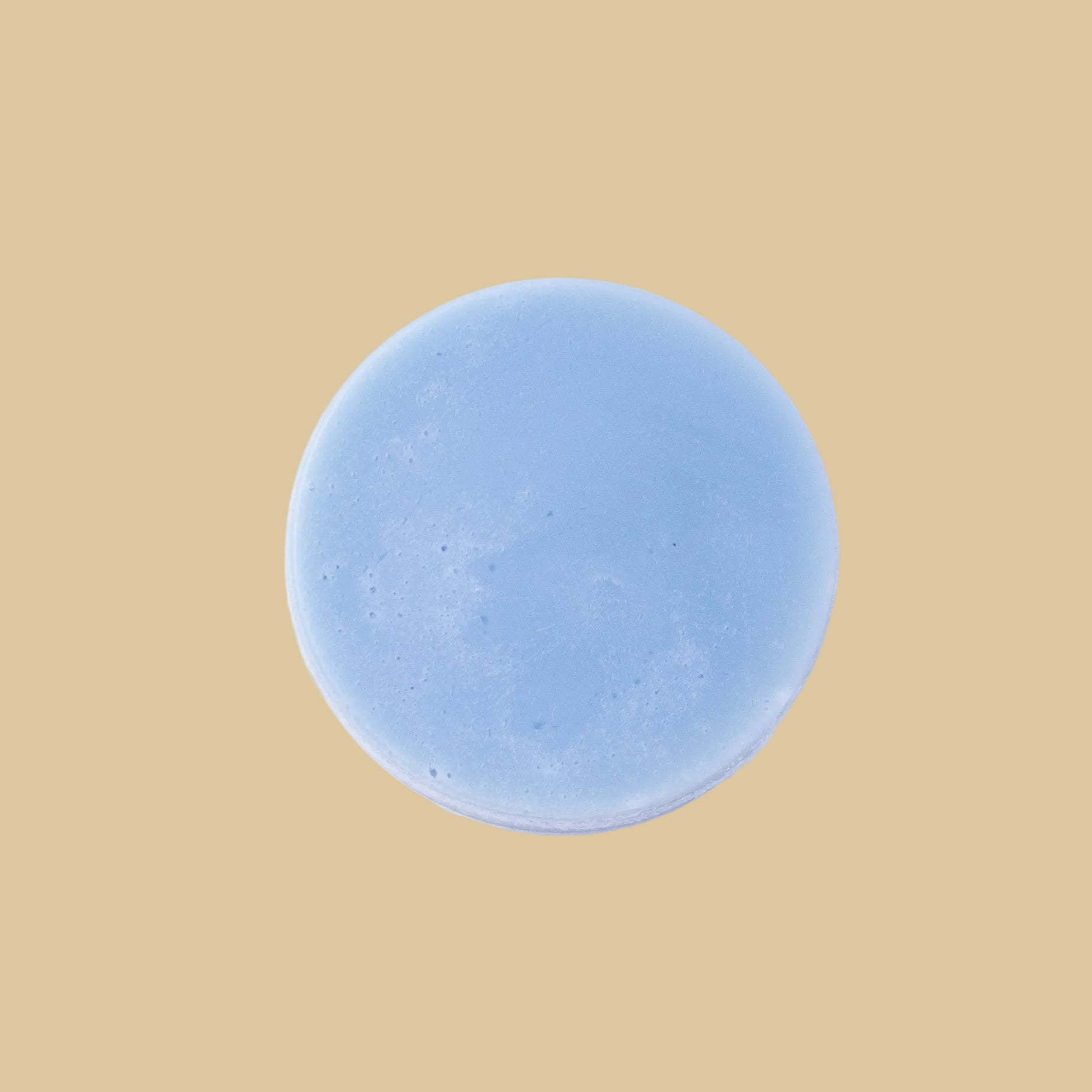 A round, light blue conditioner bar, photographed from directly above on a clean background.