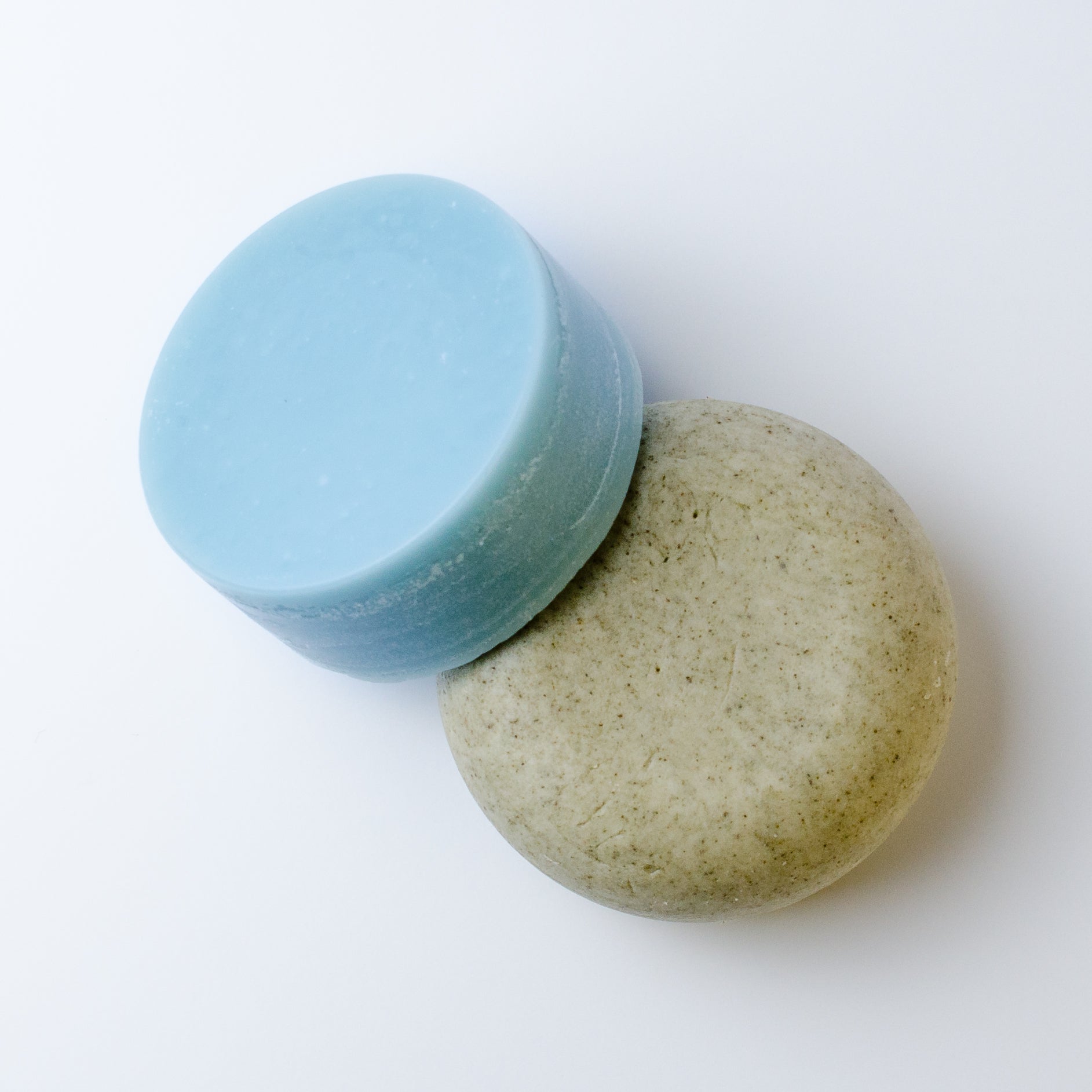 Two round shampoo and conditioner bars on a plain white background.