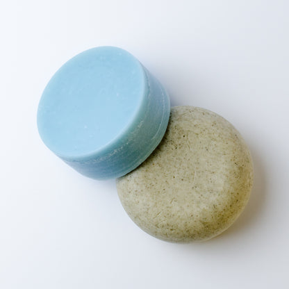 Two round shampoo and conditioner bars on a plain white background.