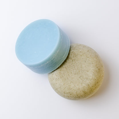 Two round shampoo and conditioner bars on a plain white background.